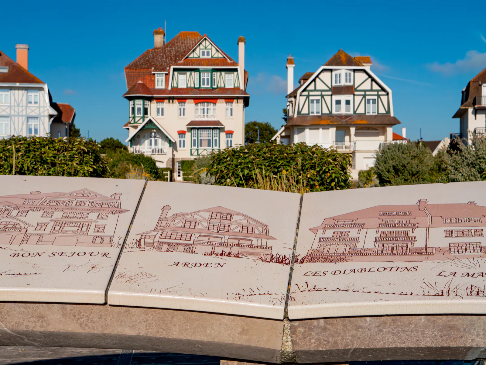 Demeures cossues d'époque avec toitures tuiles rouges et panneaux patrimoniaux gravés sur la plage